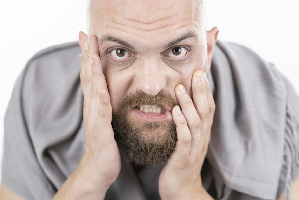 Frustrated bearded man pressing his hands to his face