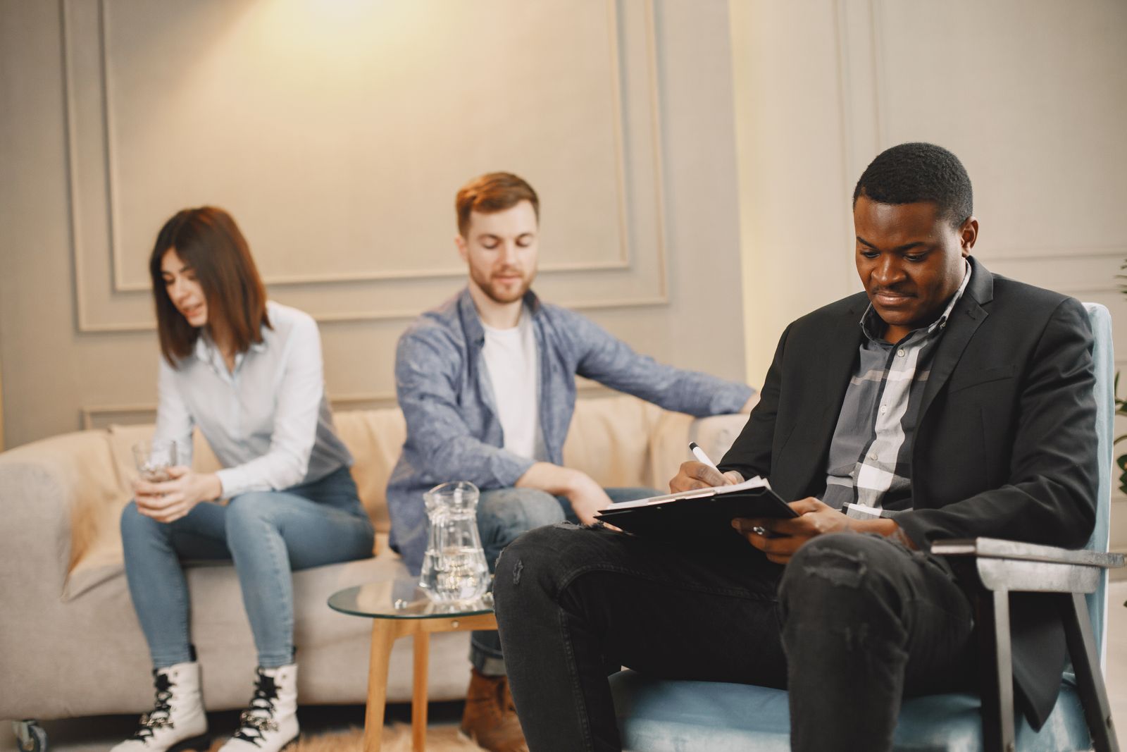 Black male therapist taking notes during a counseling session with a couple